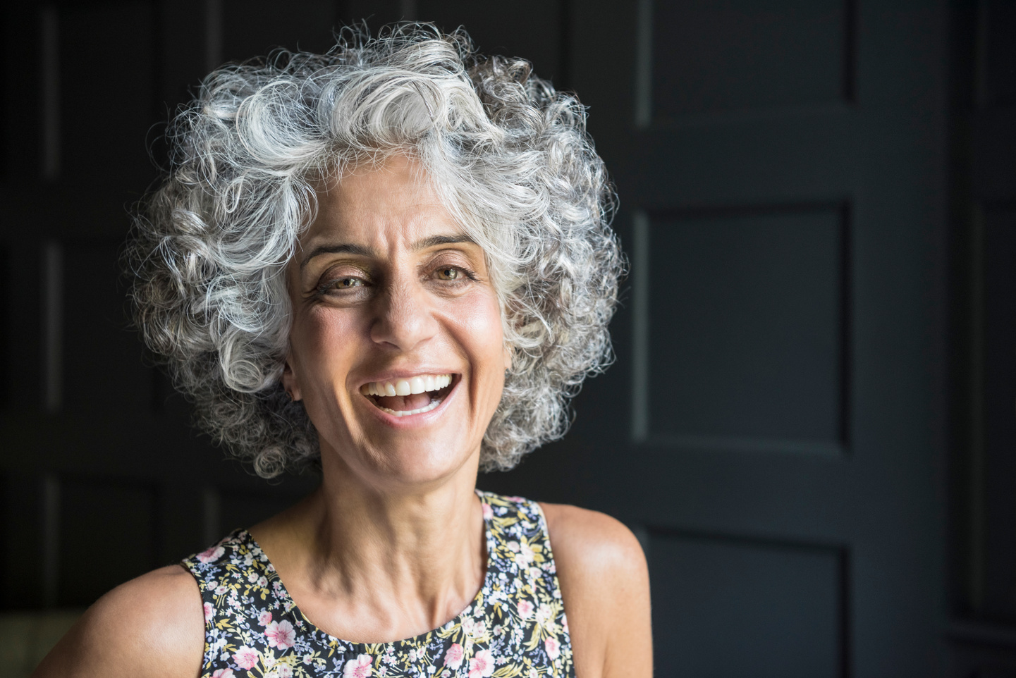 Mature woman with grey curly hair laughing
